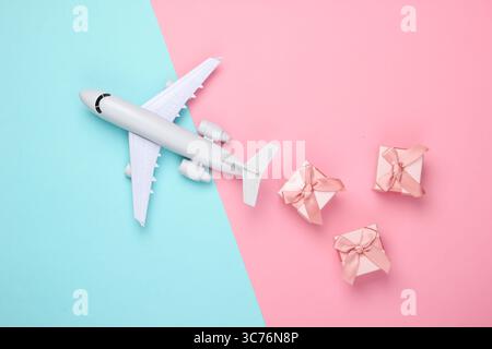Air delivery. Plane figurine and gift boxes on pink blue pastel background. Flat lay. Top view Stock Photo