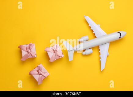 Air delivery. Plane figurine and gift boxes on a yellow background. Flat lay. Top view Stock Photo