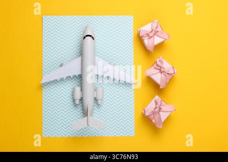 Air delivery. Plane figurine and gift boxes on yellow blue pastel background. Flat lay. Top view Stock Photo