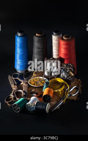 Steel scissors, Spools of thread of various colors, Thimbles in small wooden treasure chest, Sewing needles stuck in a green miniature spools thread a Stock Photo
