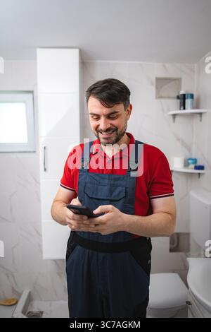 Plumber using smartphone in bathroom during house renovation Stock Photo