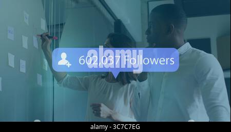 Collaborating marketing pros annotating glass board in office, pastel notes, follower count overlay Stock Photo