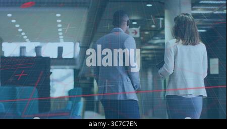 Business colleagues walking in terminal, passing blue seats windows pillars lights and arrow sign Stock Photo