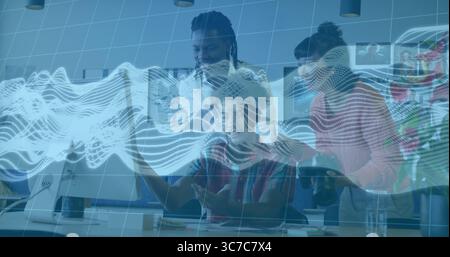 Collaborating team members analyzing data on monitor in office, with coffee mug and notepad Stock Photo
