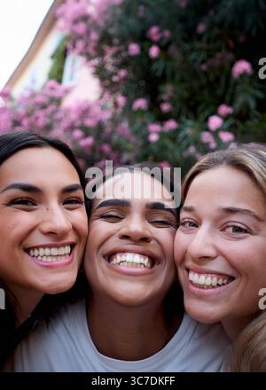 Three happy young women smiling together outdoors Stock Photo