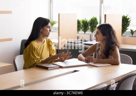 Two Indian women, colleagues, staff members brainstorming solutions in office Stock Photo
