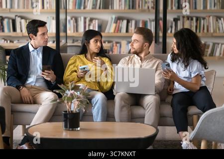 Four multiethnic teammates discussing new business application and online platform Stock Photo