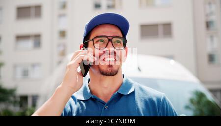 Smiling Hispanic Handyman Talking On Smartphone By Delivery Van Stock Photo