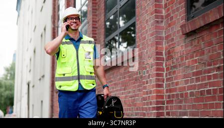 Hispanic Factory Worker Making Business Call At Construction Site Stock Photo