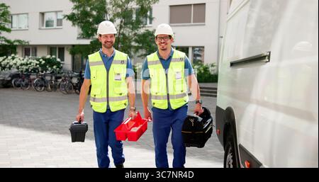 Skilled Workers On Duty, HVAC Electrician And Plumber Near Van. Stock Photo