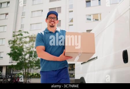 Smiling Hispanic Man Delivering Parcel From Courier Service Truck Today. Stock Photo