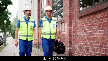Smiling Plumber And Electrician Working Together In Happy Maintenance Service. Stock Photo