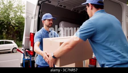 Professional Mover Unloading Boxes From Van For Delivery Service Job. Stock Photo