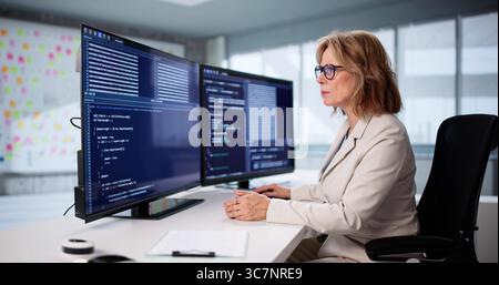 Senior Woman Coding Software On Desktop Screen As Remote Worker. Stock Photo