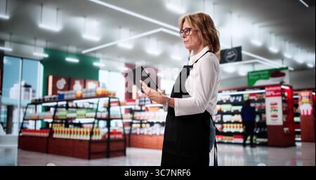 Smiling Woman Using Tablet As Retail Store Cashier In Supermarket. Stock Photo