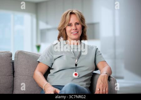 Senior Woman Feeling Secure With Emergency Alarm Button At Home Stock Photo