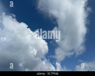 The sky is a vibrant blue, filled with puffy white clouds on a sunny day. Stock Photo