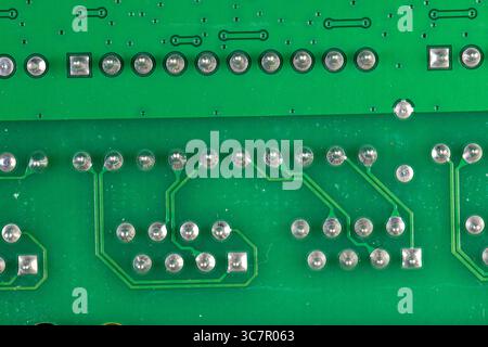 circuit board with a large number of contacts, a simple green printed circuit board with an electronic circuit with soldered elements Stock Photo