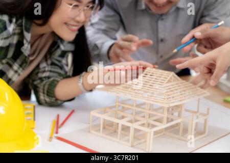 Group of architects examining a building model, discussing modern design and construction technology in a collaborative workspace. Stock Photo