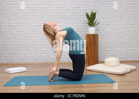 Woman doing yoga in yoga studio - camel Stock Photo