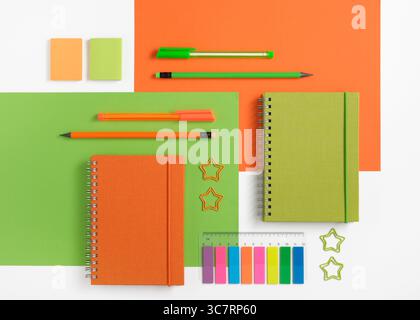 Knolling composition with different school stationery on orange and green background. Back to school Stock Photo
