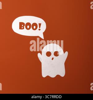 Friendly paper ghost with a bubble of text boo on an orange background Stock Photo