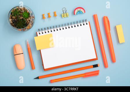Blank notebook page for your text with orange pen and pencil on blue background. Eraser in form of rainbow. Stock Photo