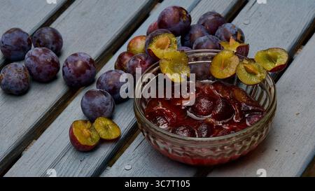 Wild plums on a wooden surface. Plum compote in a glass bowl. Stock Photo