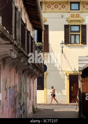 Street scene of man looking at phone and shadows on wall in Salo on Lake Garda, Italy Stock Photo