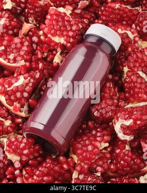A plastic bottle of pomegranate juice without a label lies in pomegranate seeds Stock Photo