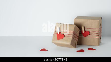 Two brown craft gift boxes with red paper heart on white background with copyspace. Valentine's Day gift. Stock Photo