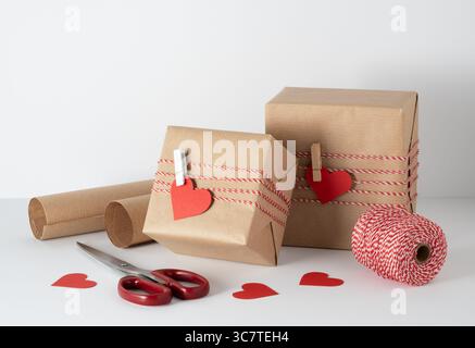 Two craft brown boxes with red paper hearts on clothespins. Gift wrapping idea. Stock Photo