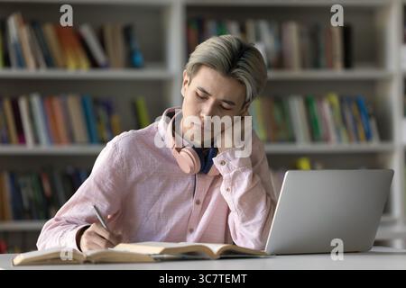 Serious busy male student prepare assignment take notes at desk Stock Photo