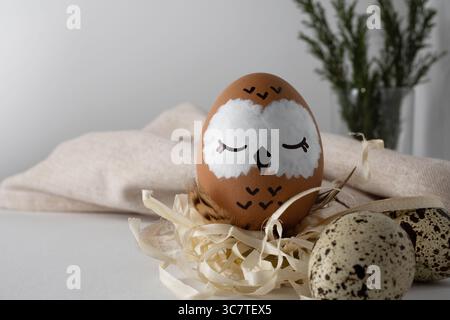 Cute sleeping owl. A brown Easter egg in a straw nest. Stock Photo
