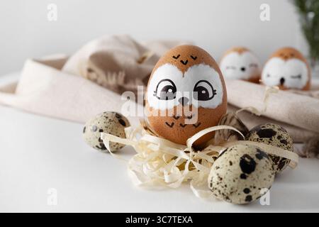 Funny owl. Brown Easter eggs, quail eggs on yellow straw. Light background. Stock Photo