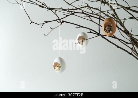Easter decoration of eggshells and quail eggs on branches. Light background, space for text, selective focus, horizontal Stock Photo