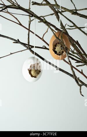Easter decoration of eggshells and quail eggs on branches. Light background, space for text Stock Photo