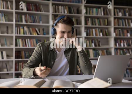 Young male student in earphones attend virtual lecture using notebook Stock Photo
