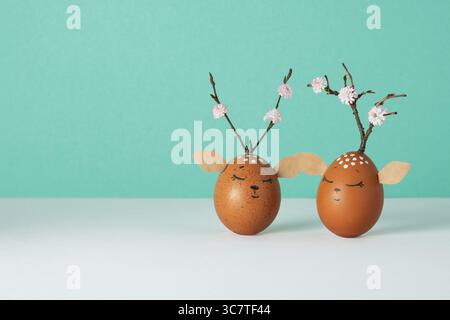 Funny deers made of eggs on white and pastel green background. Brown Easter eggs decoration. Space for your text. Stock Photo