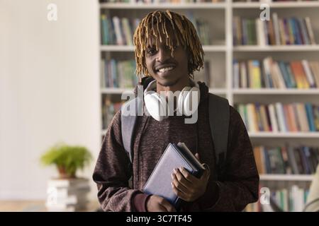 Portrait happy teen guy student smiling at camera in library Stock Photo