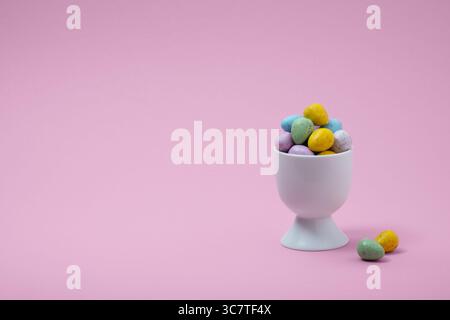 Multicolored chocolate eggs in a white egg stand on a pink background Stock Photo