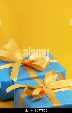 Blue gift boxes with yellow ribbons on a yellow background. Space for your text. Stock Photo