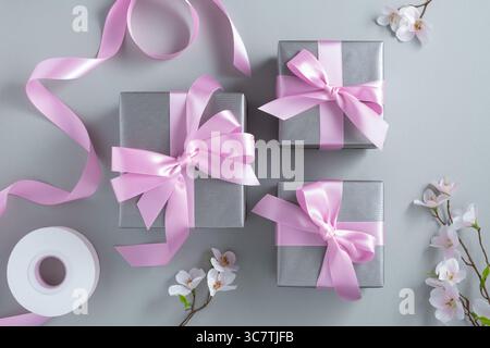 Silver gift boxes with pink bows on a gray background. Stock Photo