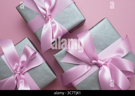 Silver gray gift boxes with pink satin bows on pink background. Surprise present. Stock Photo