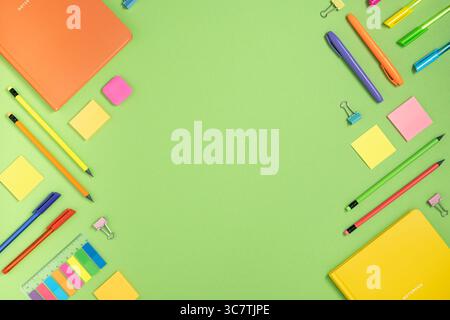 Frame of colorful school and office stationery on green background. Flatly, copyspace. Stock Photo