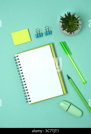Open notebook with space for your text with green pen, pencil and marker on pastel green background. Flatly. Stock Photo