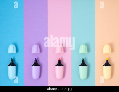 Pastel color highlighter markers on pink, blue, yellow, green and purple background. Flatly, copyspace. Stock Photo