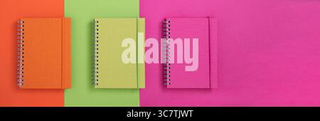 Banner with colorful notebooks on orange, green and pink background. Back to school banner. Stock Photo
