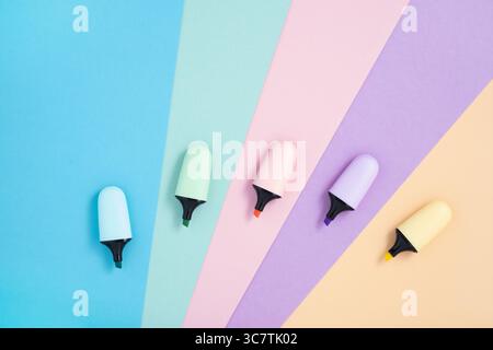 Stationery background with pastel color highlighter markers on pink, blue, yellow, green and purple. Flatly, copyspace. Stock Photo