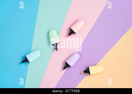 Stationery background with pastel color highlighter markers on pink, blue, yellow, green and purple. Flatly, copyspace. Stock Photo